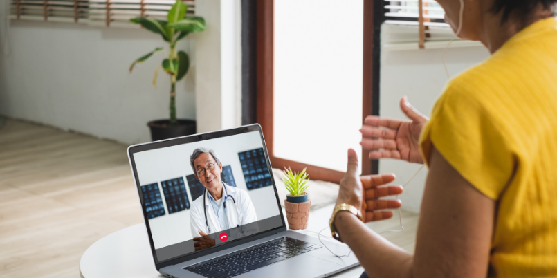 Woman using video call with doctor on laptop.