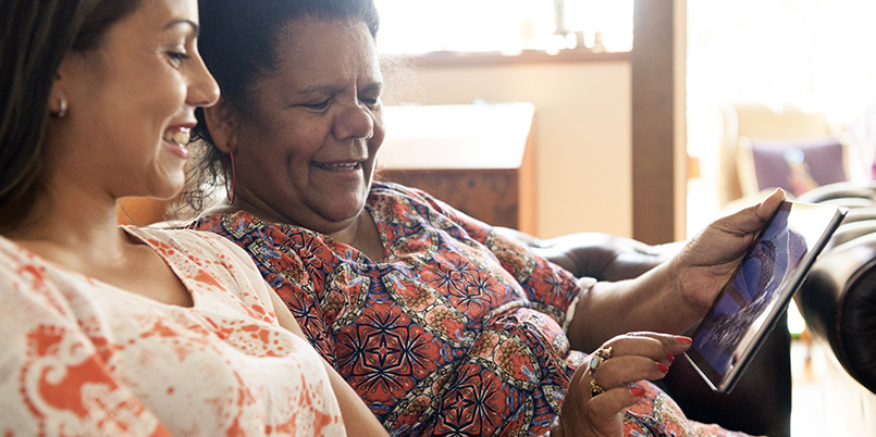 Two women at home using digital tablet