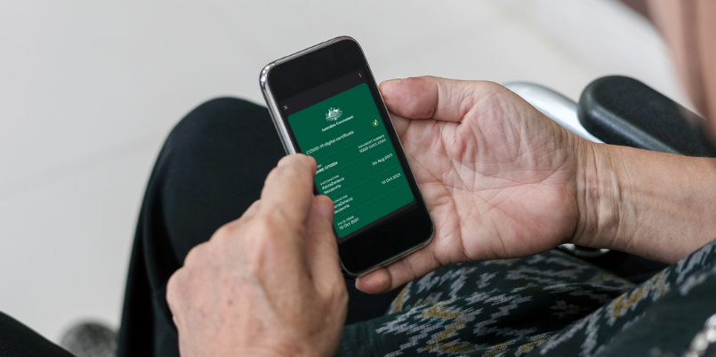 Woman holding a mobile phone. A COVID-19 digital certificate is displayed on the screen.