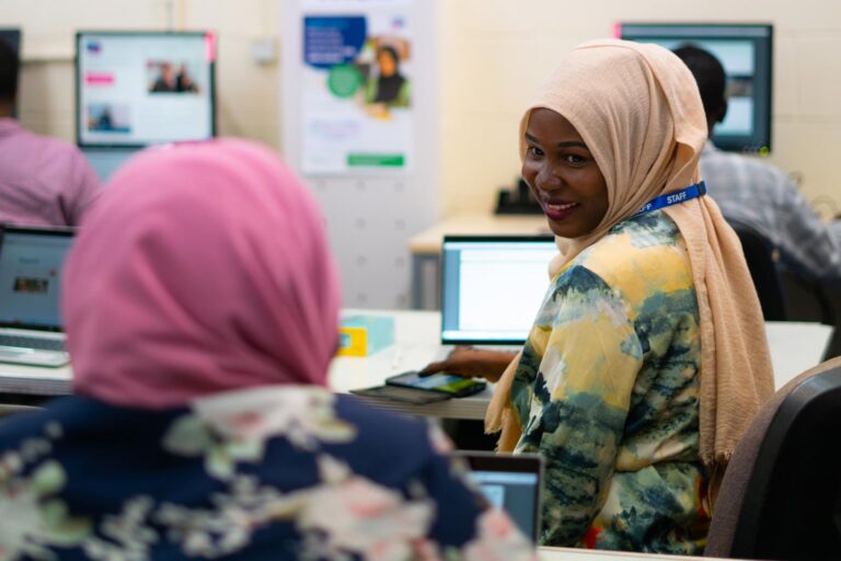 Women wearing headscarfs smiling and using computers