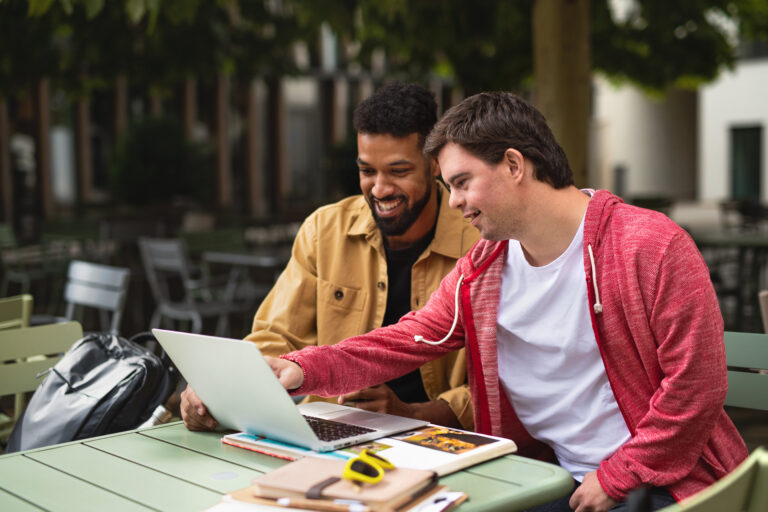 young man with intellectual disability using a laptop with a friend