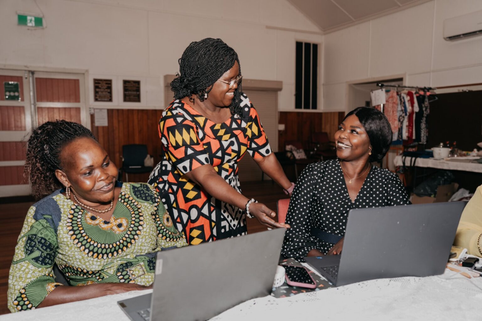 Two women using a computer and being helped by another woman