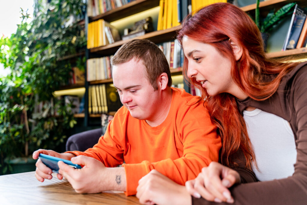 Young man with Down syndrome and his tutor studying indoors